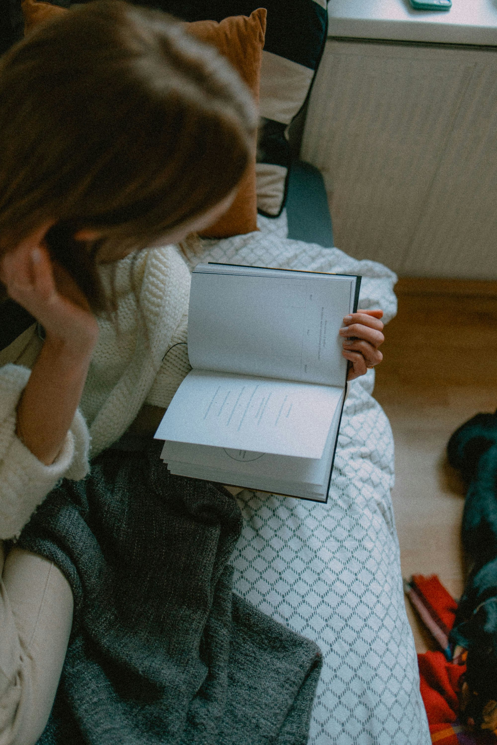 woman in white sweater holding white book